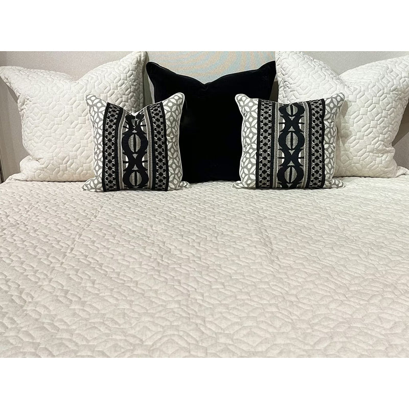 Decorative pillows on a bed with a quilted headboard